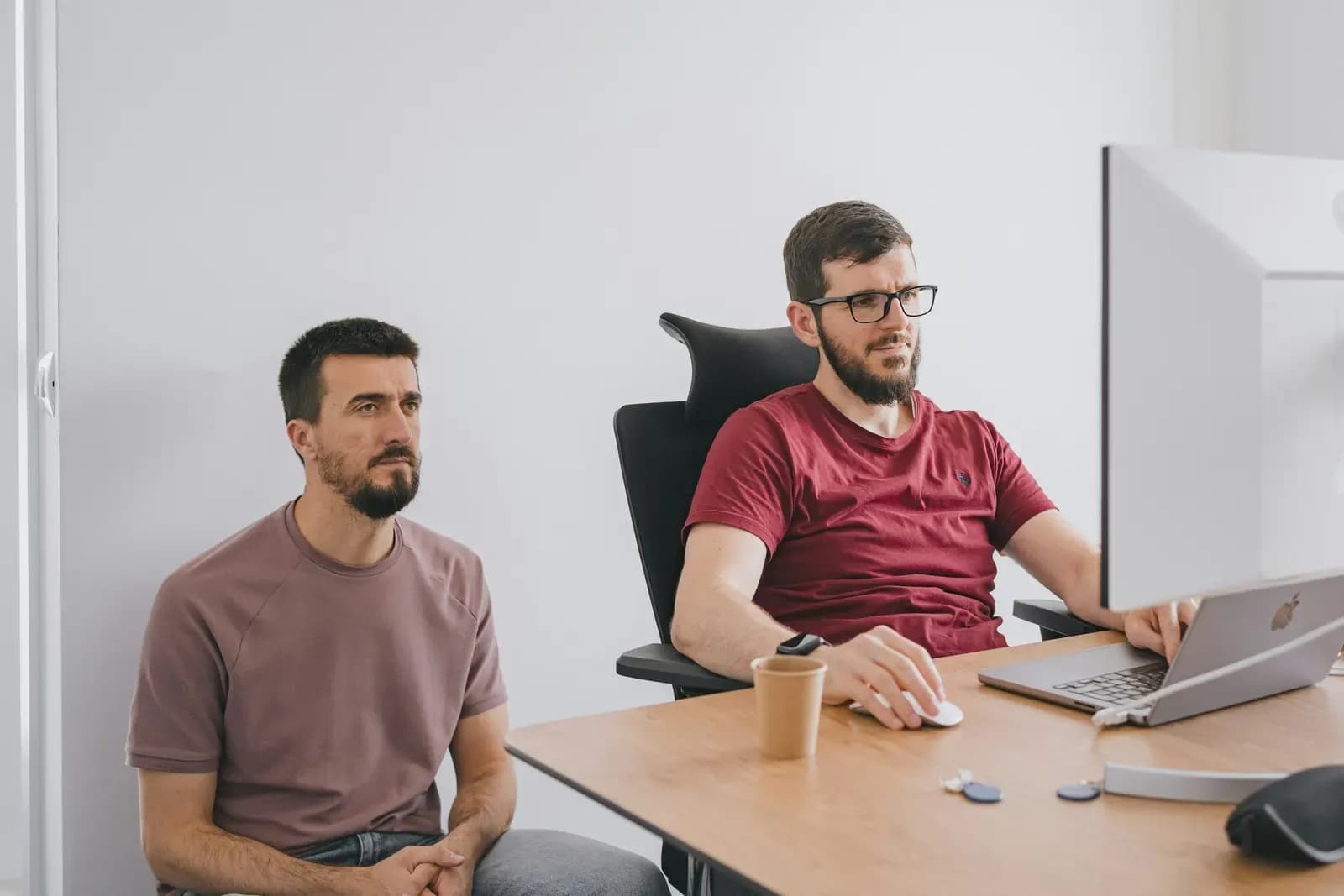 Dois colegas olhando para uma tela de computador em um escritório claro