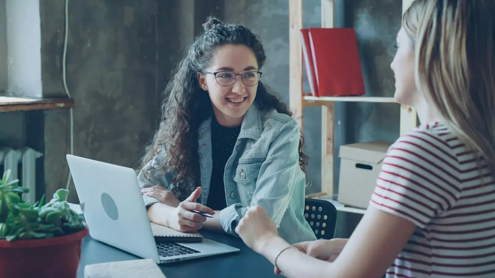 Duas pessoas conversando perto de um notebook em uma mesa